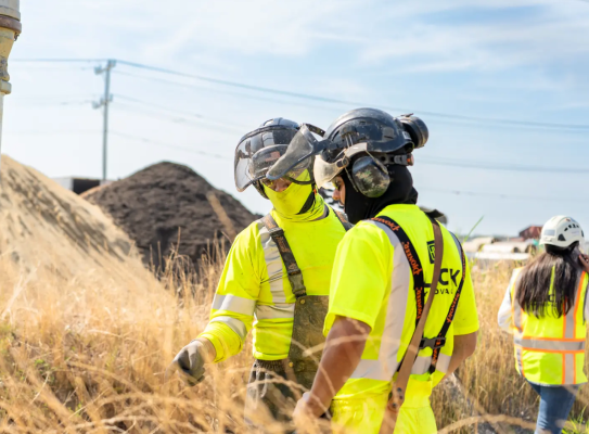 Two workers near field having a discussion.