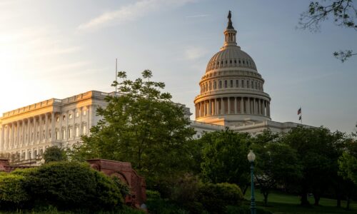 A government building with a dome, possibly a state capitol, surrounded by trees.